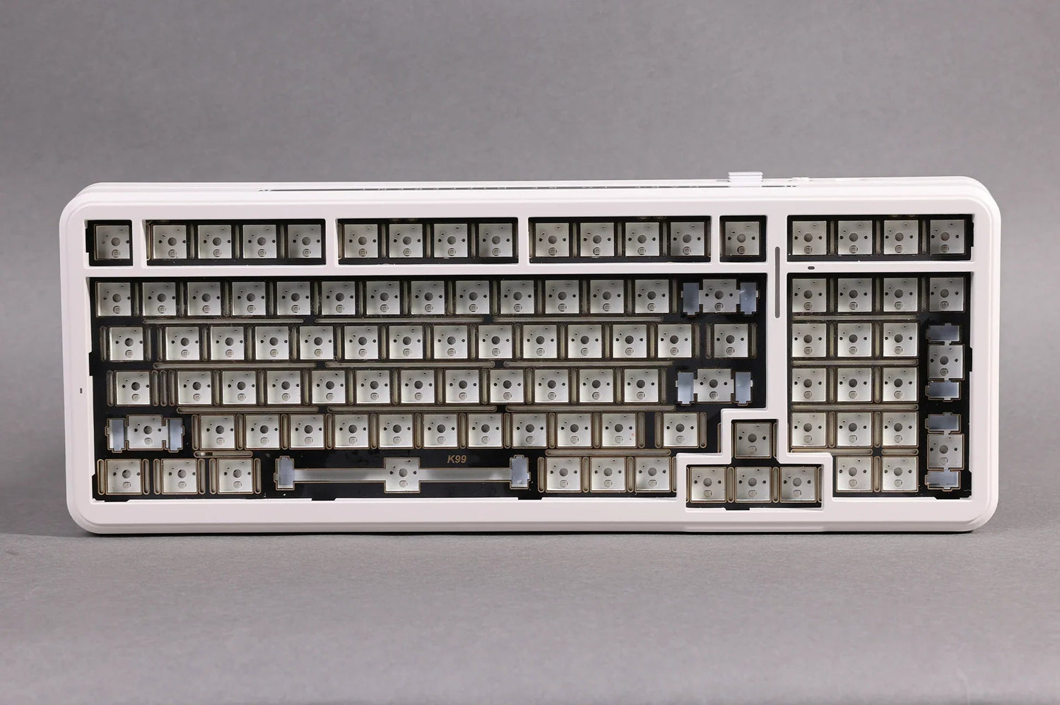 White mechanical keyboard frame with K99 label, showing empty key switches and mounting points for custom keycaps.