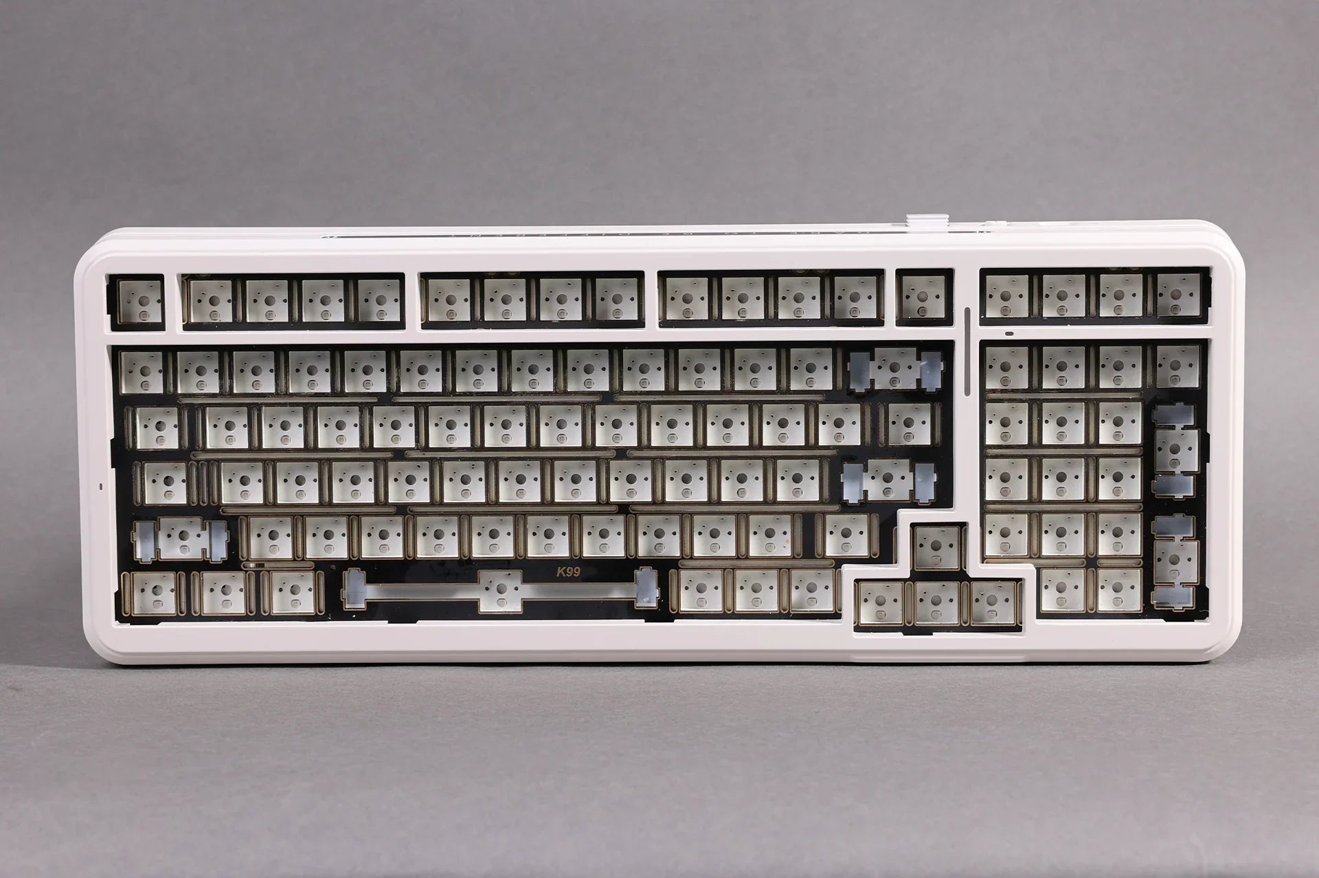 White mechanical keyboard frame with K99 label, showing empty key switches and mounting points for custom keycaps.