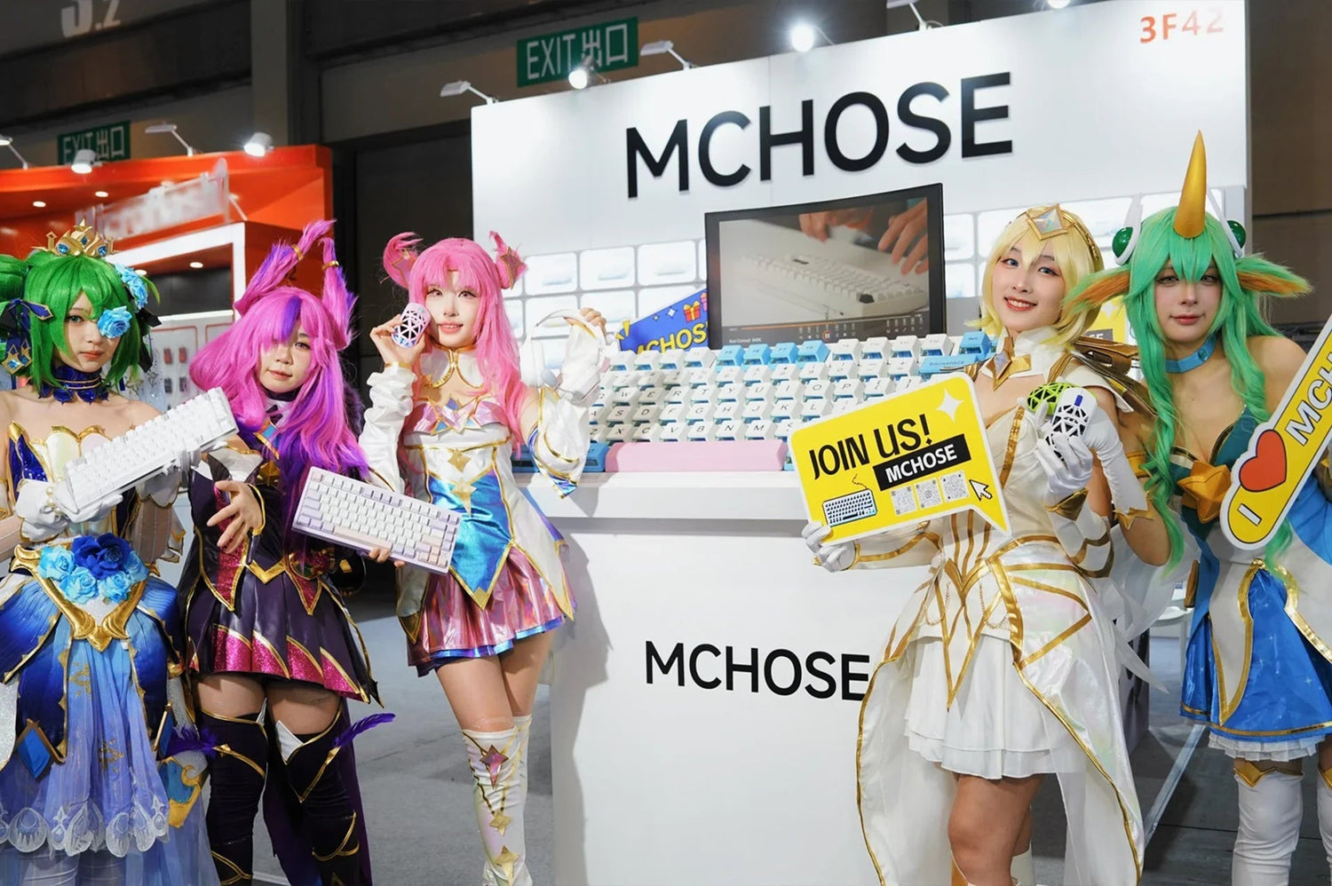 Cosplayers showcasing MCHOSE mechanical keyboards at gaming expo booth with colorful costumes and promotional signs